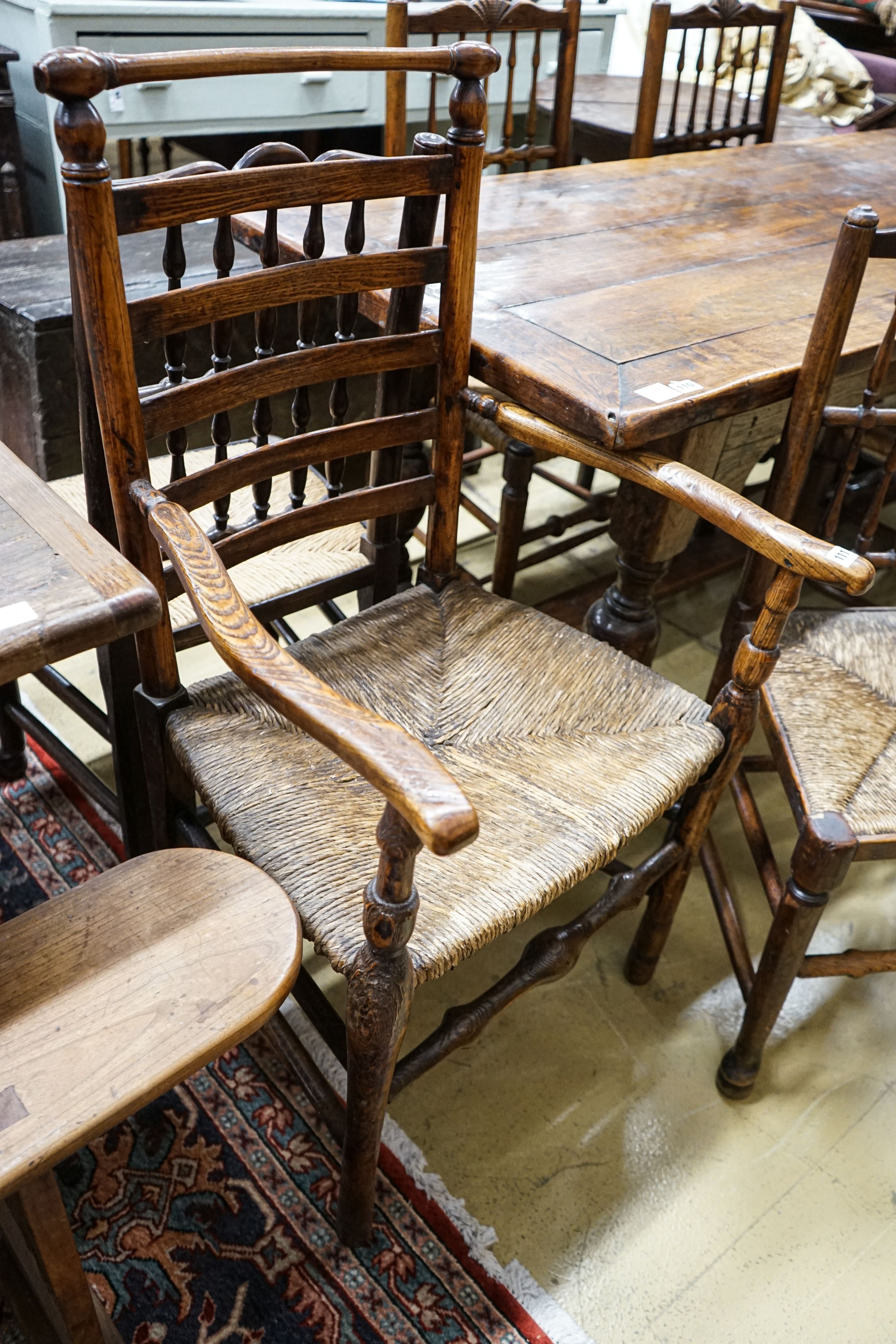 A harlequin set of five oak, elm and beech spindle back chairs, with rush seats and a similar ladderback carver